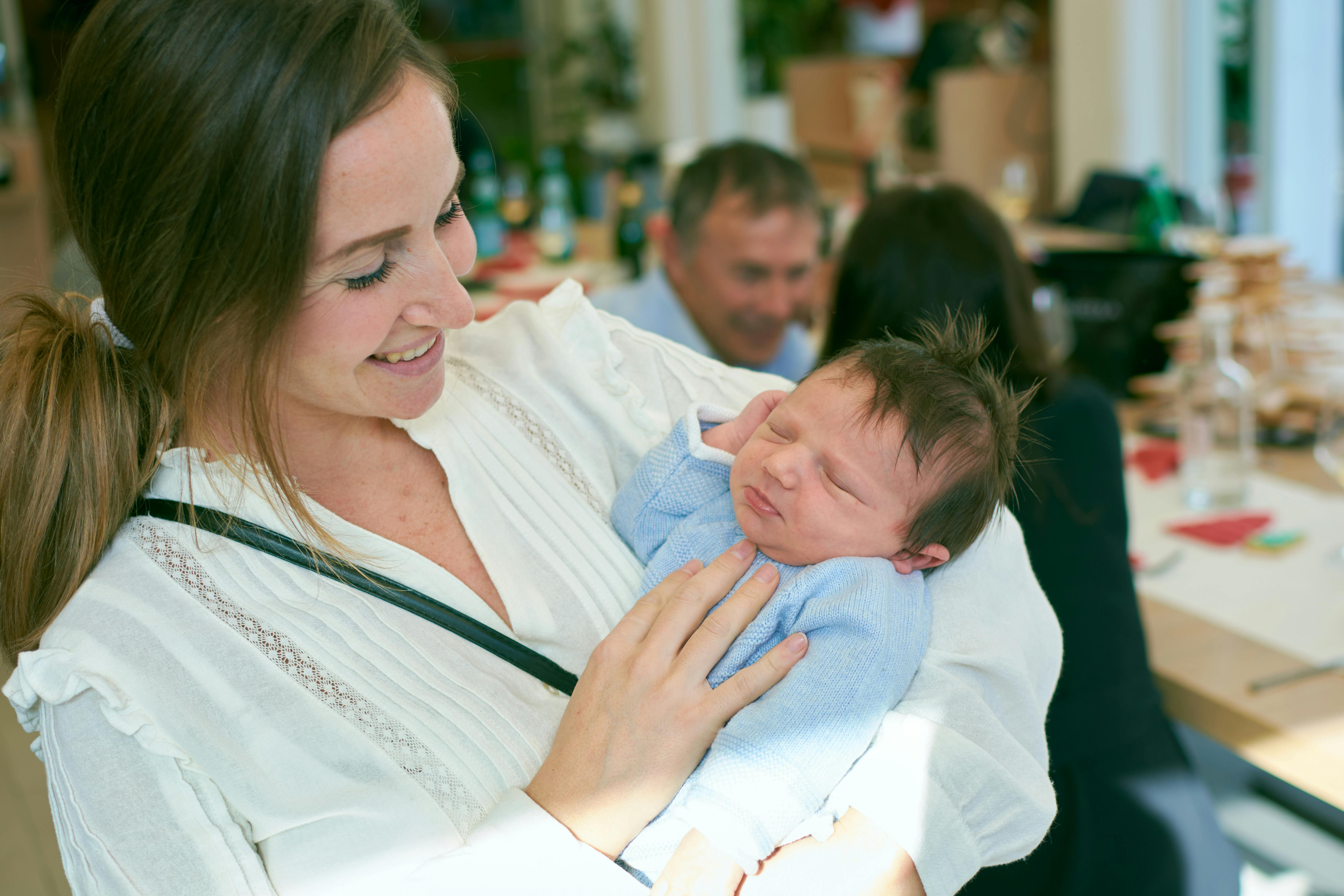 Smiling woman holding a sleeping newborn in a hospital room